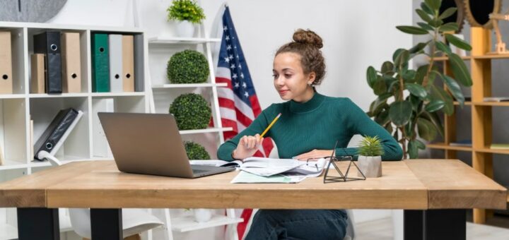 a girl studying while at the desk with a laptop on the desk in the office