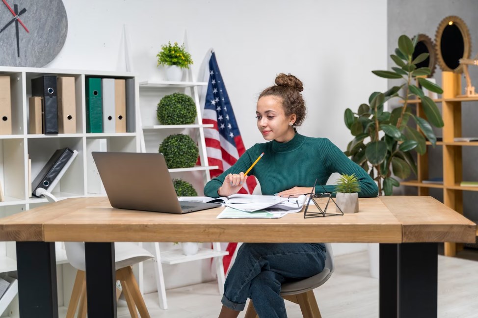 a girl studying while at the desk with a laptop on the desk in the office