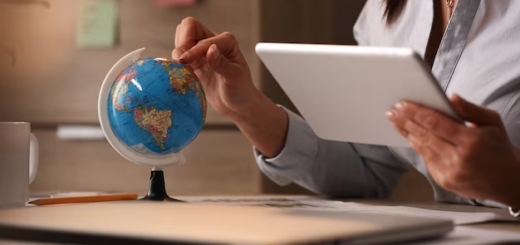 Hand holding a tablet and pointing on a globe with the other hand
