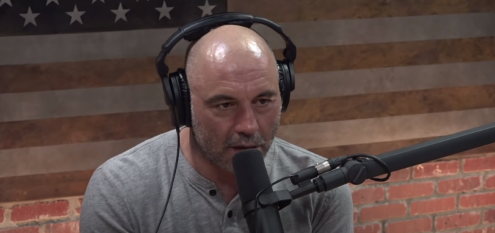 Joe Rogan in gray shirt, wearing headset, speaking into microphone