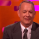 Tom Hanks in a suit against an orange background