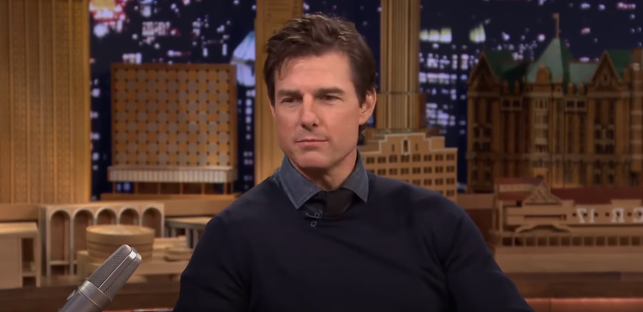 Tom Cruise during an interview with a backdrop of a building