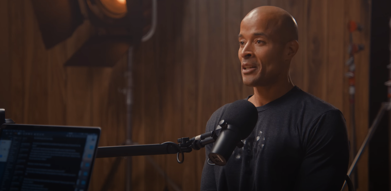 David Goggins speaking into a microphone wearing black attire