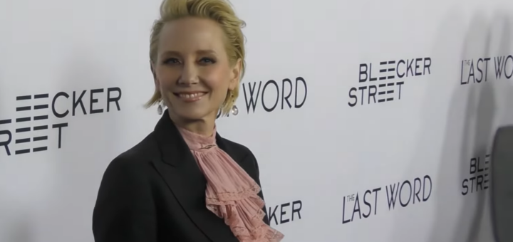 Anne Heche in a classic black suit smiling and looking on the camera