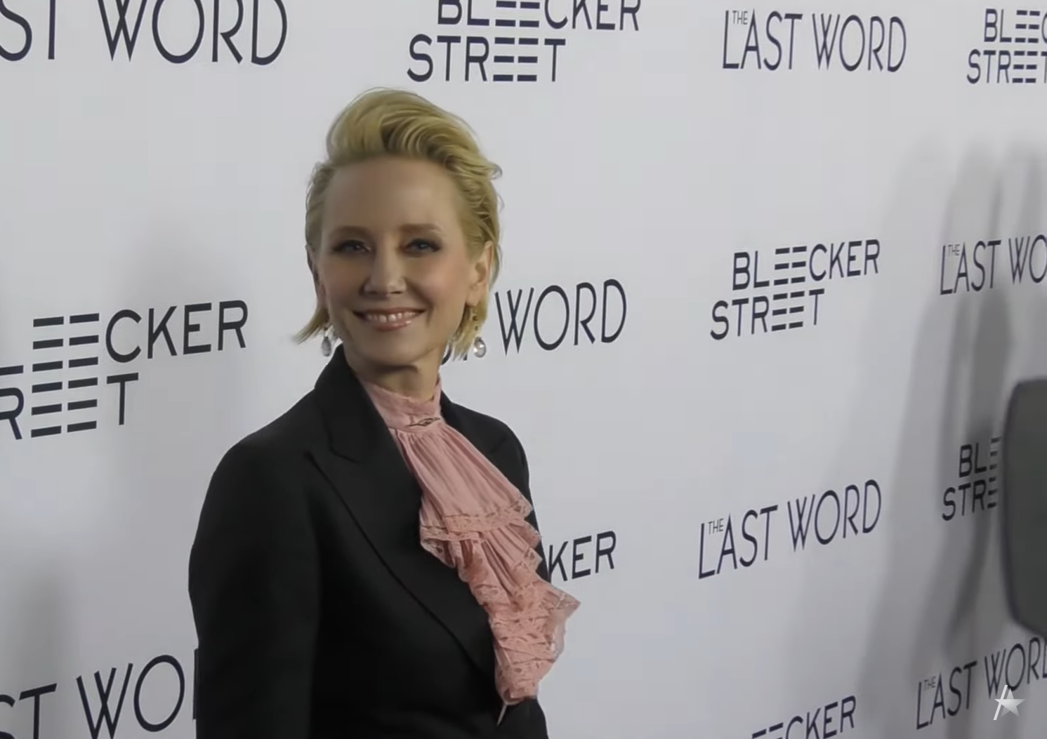 Anne Heche in a classic black suit smiling and looking on the camera